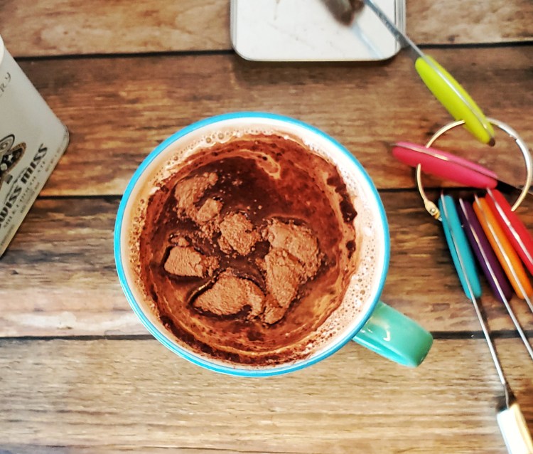 cocoa mix floating in a cup of hot milk before being stirred in
