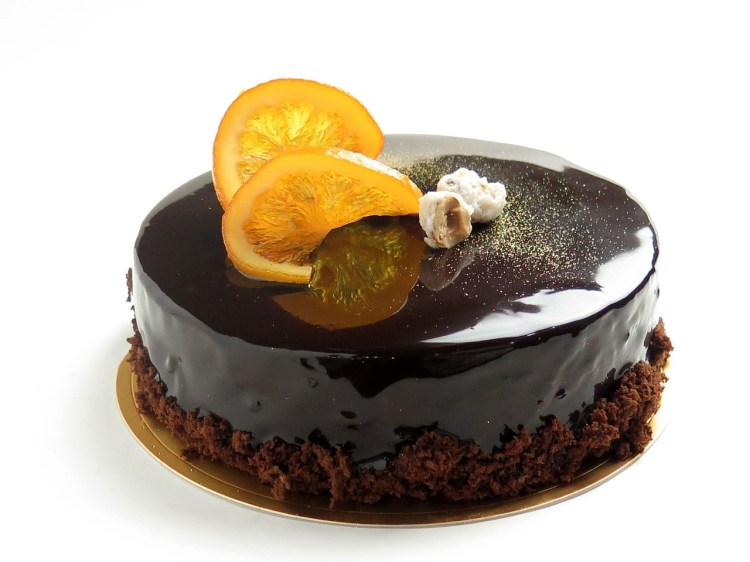decadent-looking chocolate cake, with a mirror glaze, and topped with candied orange slices